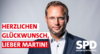 Porträtfoto des neuen Ulmer Oberbürgermeisters Martin Ansbacher. Davor in roter und weißer Schrift: "Herzlichen Glückwunsch, lieber Martin!". Unten rechts in weiß das Logo der SPD Baden-Württemberg.